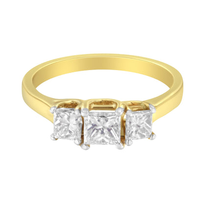 Front angle view of a yellow metal ring with three prong-set white princess-shaped gemstones.