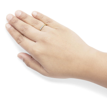 Yellow ring with five round white gemstones in prong settings, worn on a model's hand, shown from above.
