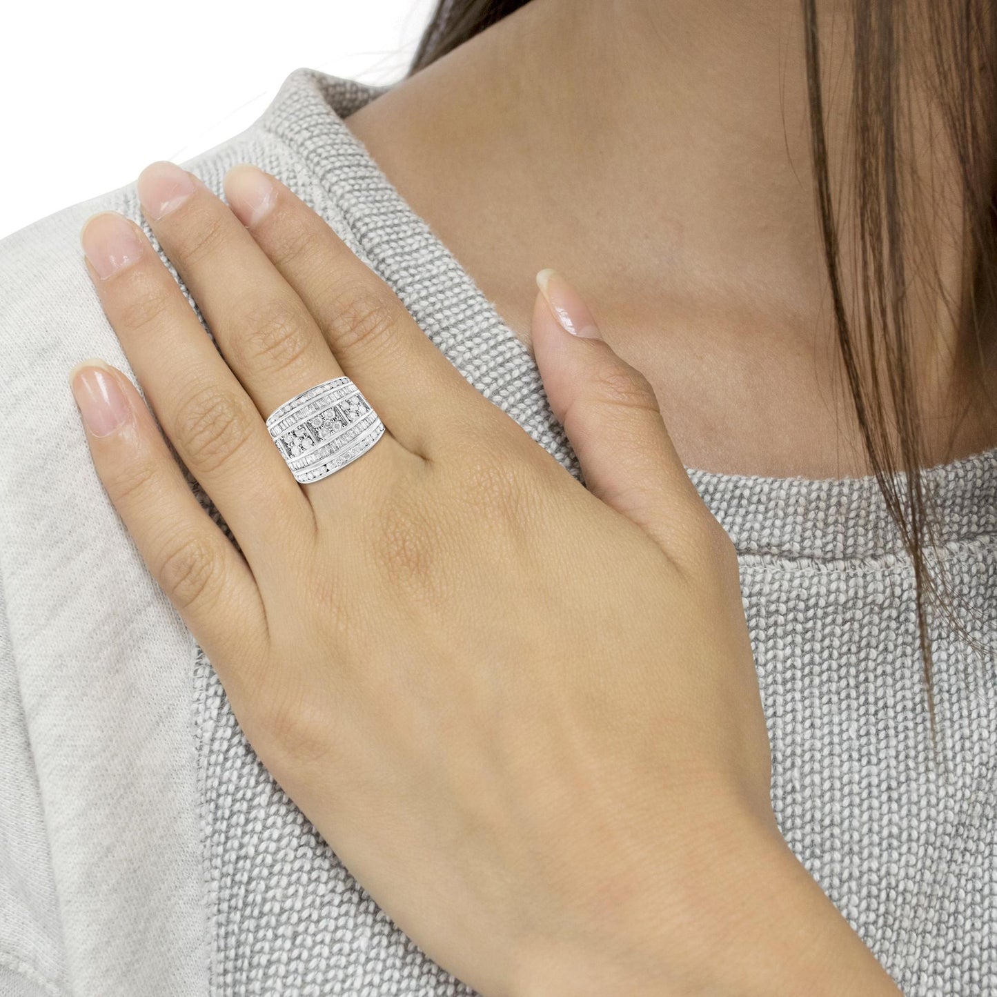 White metal ring with multiple rows of round and baguette white gemstones in channel settings, worn on a model's hand, shown from a front angle.