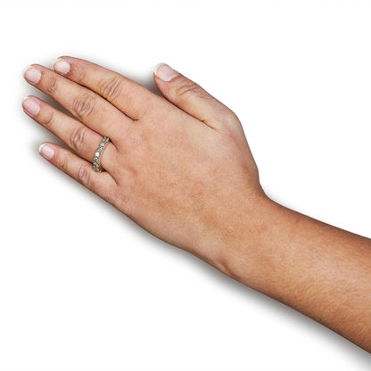 Yellow ring with round white gemstones in shared prong setting on a model's hand, shown from top angle.