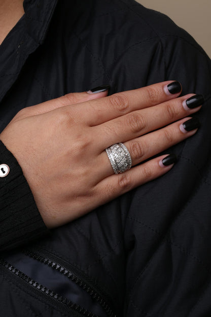 Close-up of a hand on a black jacket wearing a white metal ring with round prong-set white gemstones and baguette channel-set white gemstones, shown from a side angle.