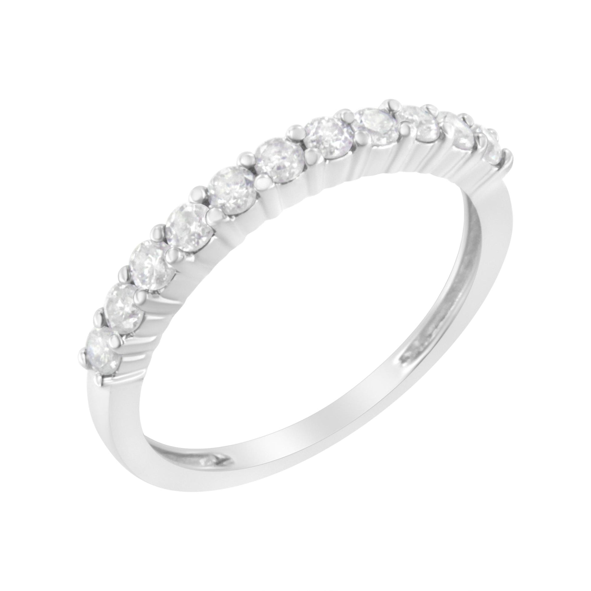 White metal ring with round white gemstones in prong settings along the top, shown from a side angle.