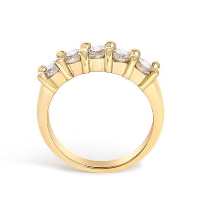 Yellow metal ring with five round white gemstones set in prongs on the top, shown from a side angle.