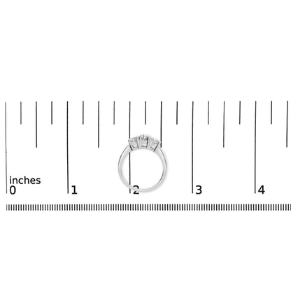 Top view of a white ring with three round white gemstones in four-prong settings, placed on a ruler for size reference.