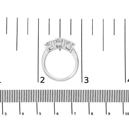 Top view of white metal ring with three white gemstones in four-prong settings, placed on a ruler for size reference.