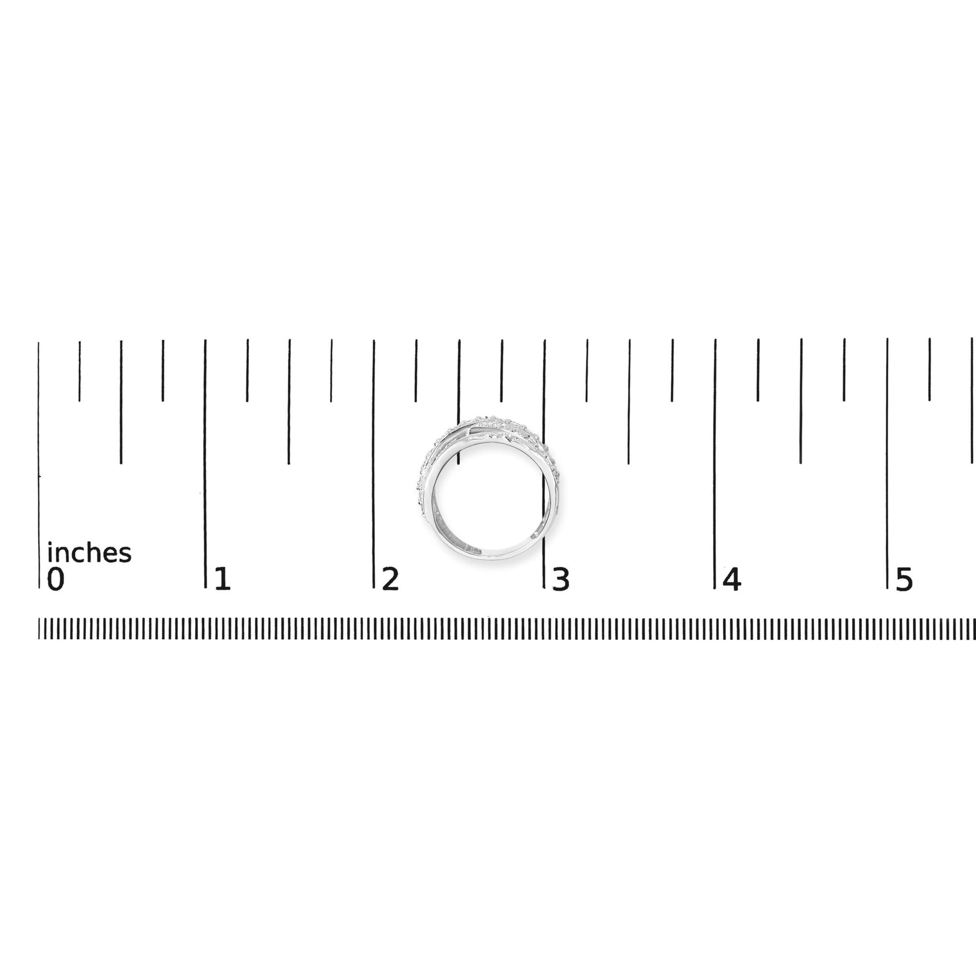 White metal ring with multiple overlapping bands encrusted with round white gemstones in prong settings, shown at front angle with size comparison on a ruler and coins.