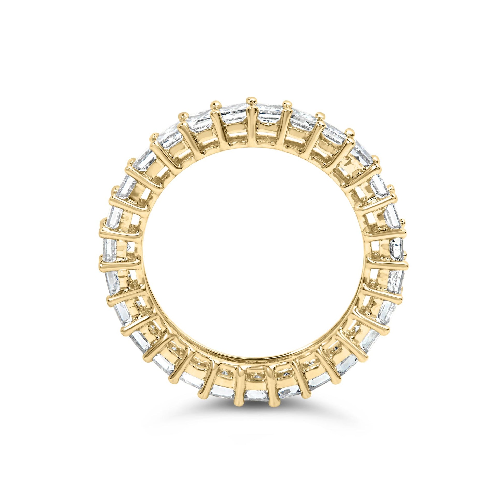 Top-down view of a yellow metal ring with white princess-shaped gemstones set in prongs encircling the band.