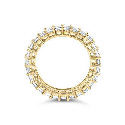 Top-down view of a yellow metal ring with white princess-shaped gemstones set in prongs encircling the band.