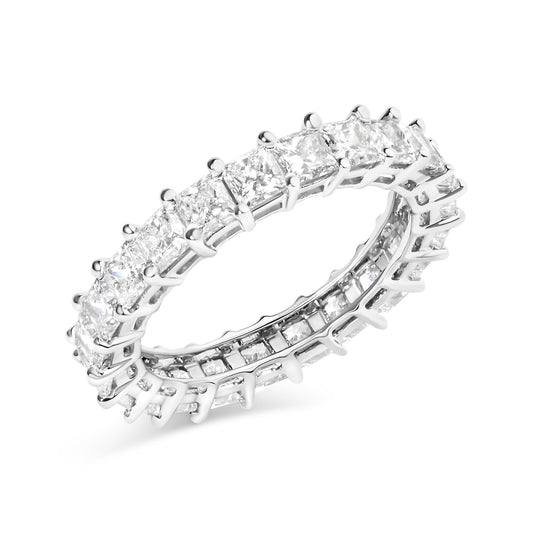 White metal ring with princess shape white gemstones in a shared prong setting, shown at an angled close-up view.