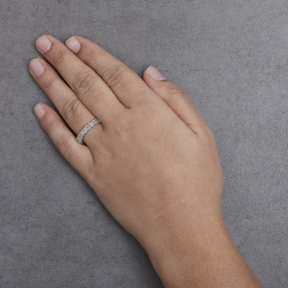 White metal ring with princess-shaped white gemstones in shared prong setting on a model's hand, angled top-down.