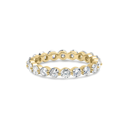 Yellow metal ring with round white gemstones in prong settings around the band, shown from a slightly elevated front angle.