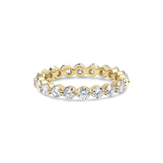Yellow metal ring with round white gemstones in prong settings around the band, shown from a slightly elevated front angle.