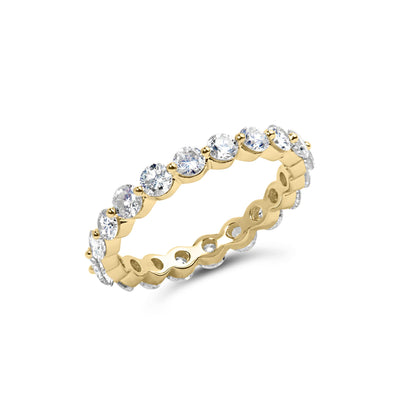 Yellow metal eternity band ring with round prong-set white gemstones, shown at an angled close-up.