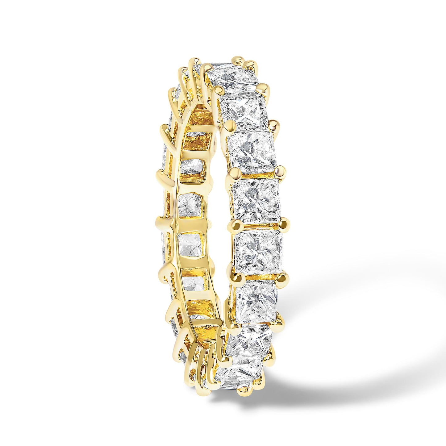 Yellow metal ring with princess-shaped white gemstones in prong settings all around, shown in a close-up angled view.