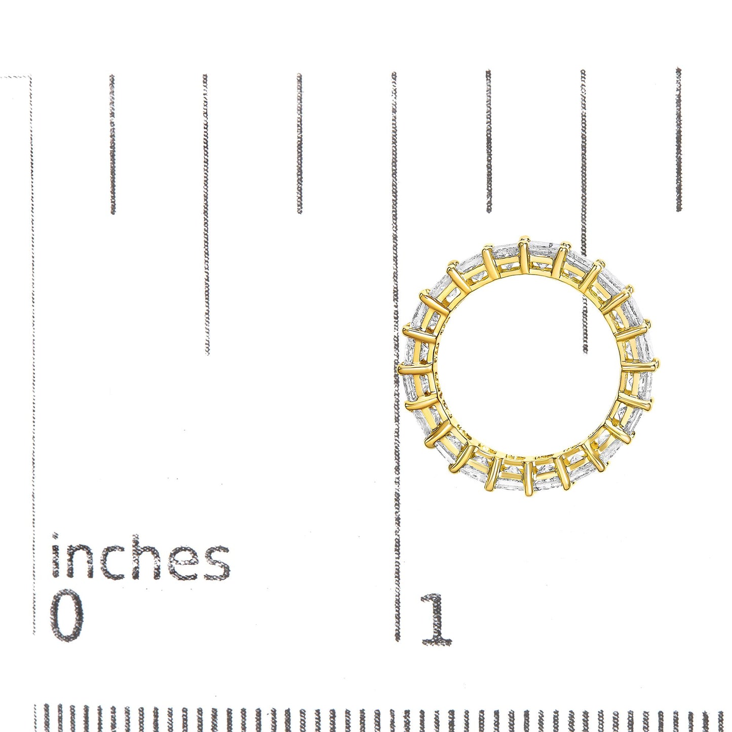 Top-down view of a yellow metal ring with white princess-shaped gemstones in a prong setting, placed on a ruler for size reference.