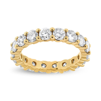 Close-up front angle of a yellow metal eternity ring set with round prong-set white gemstones all around.