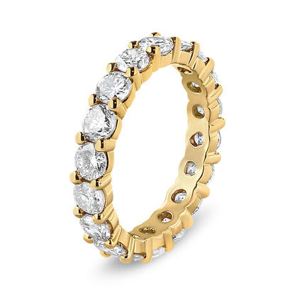 Ring with yellow metal band featuring round white gemstones in prong settings all around, shown at an angled view.