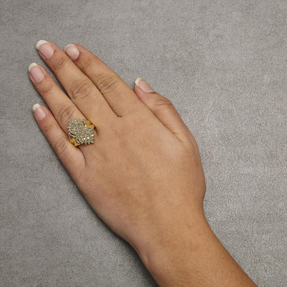 Yellow metal ring with two cluster arrangements of round, prong-set champagne-colored gemstones, worn on a model's hand, shown from a top angle.