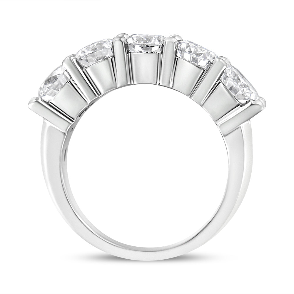 White metal ring with five round white gemstones in shared prong setting, shown from side angle.