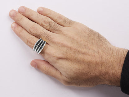 Close-up front angle of a yellow metal ring with multiple rows of prong-set black and white round gemstones, worn on a model's hand.