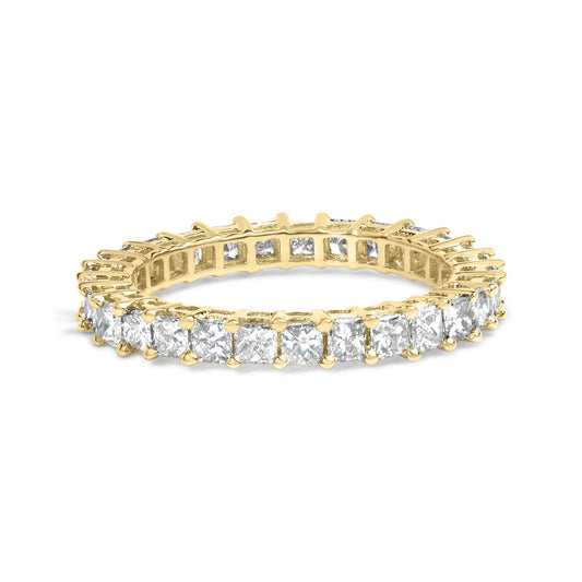 Yellow metal ring with princess-shaped white gemstones in a shared prong setting, shown in a close-up angled shot.