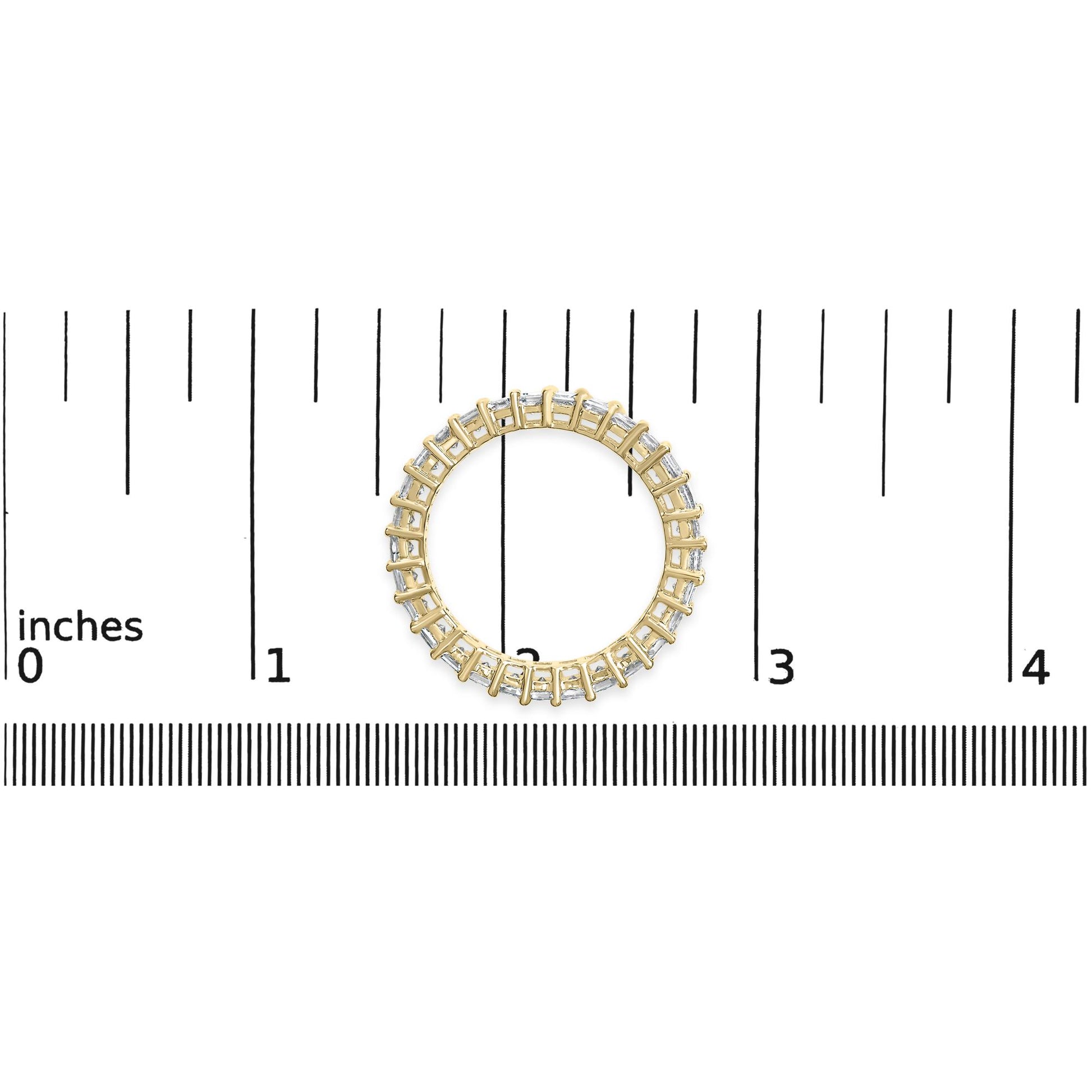 Top-down view of a yellow metal ring with white princess-shaped gemstones in a shared prong setting, placed on a ruler for size reference.