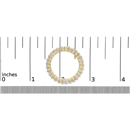 Top-down view of a yellow metal ring with white princess-shaped gemstones in a shared prong setting, placed on a ruler for size reference.