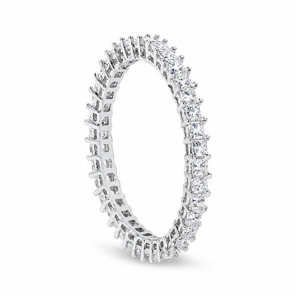 Close-up front angled shot of a white metal ring featuring princess shape white gemstones in prong settings encircling the entire band.