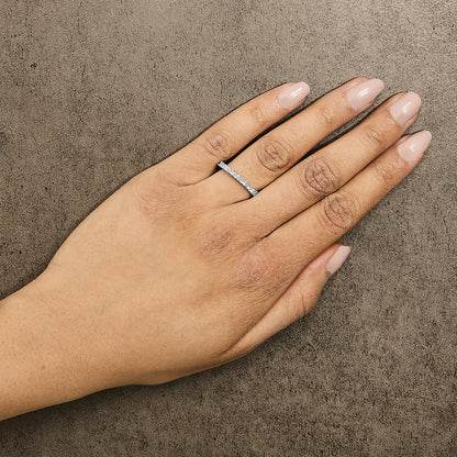 Close-up side angle of a model's hand wearing a white ring featuring princess-shaped white gemstones in a prong setting all around the band.