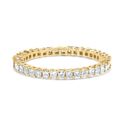 Close-up angled view of a yellow metal ring featuring a continuous row of white princess-shaped gemstones in prong settings around the band.