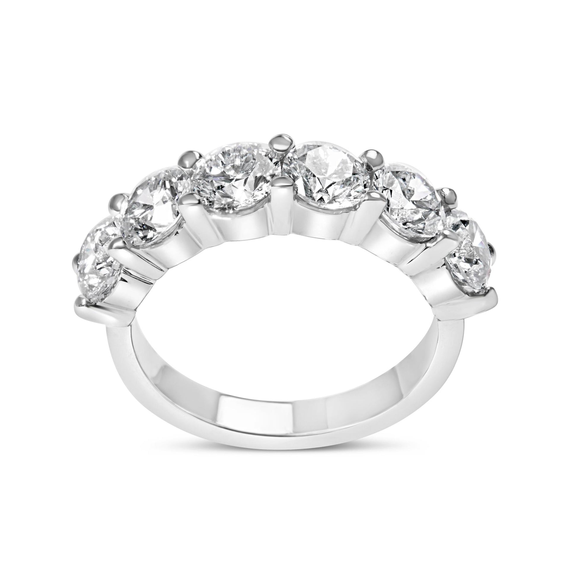 White metal ring with six round white gemstones in shared prong setting, side angle view.