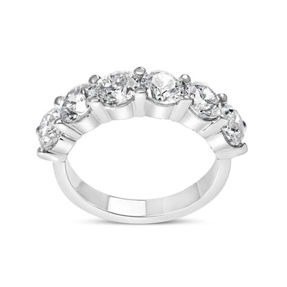 White metal ring with six round white gemstones in shared prong setting, side angle view.