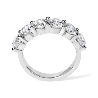 Close-up front angle of a white ring featuring a row of six round white gemstones in a shared prong setting.