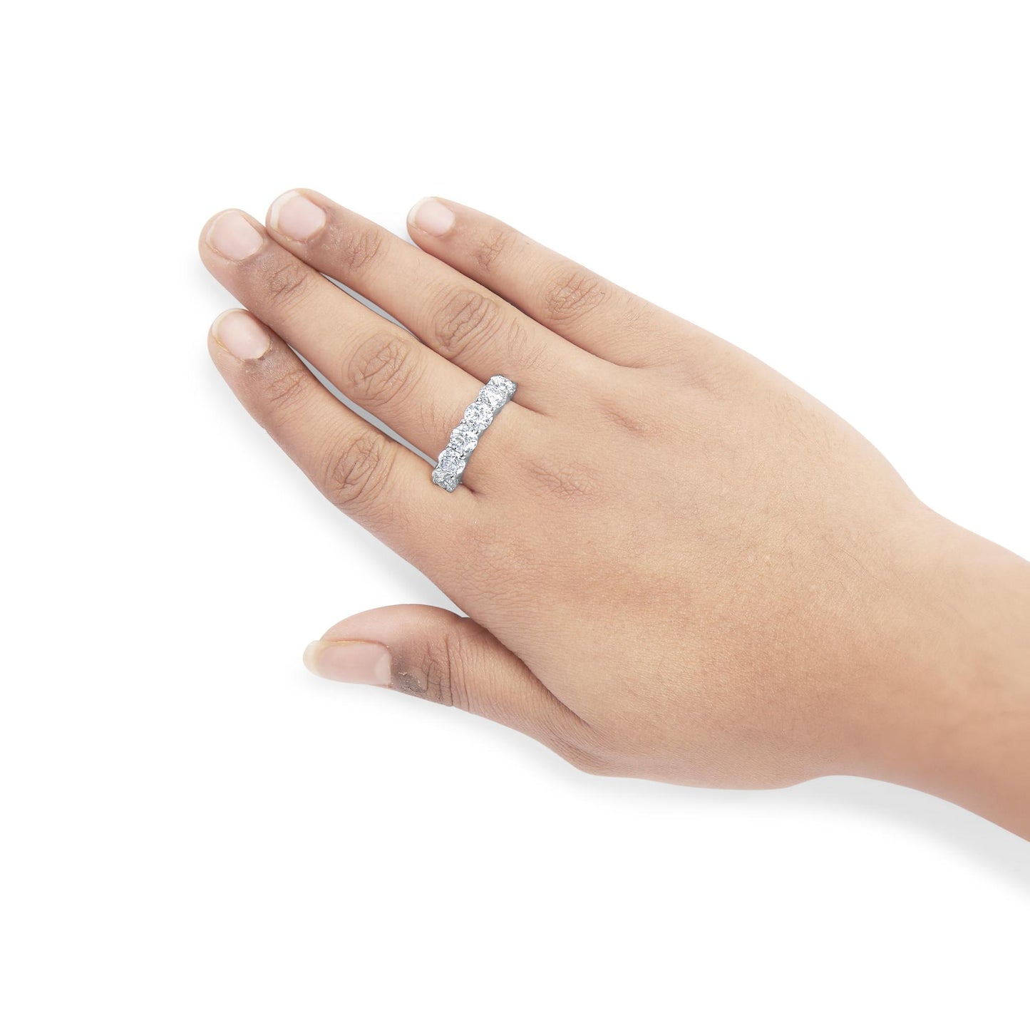 White metal ring with round white gemstones in shared prong setting worn on a hand, top-down angle.