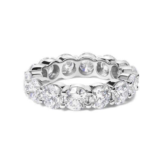 White metal eternity band ring with round white gemstones in shared prong setting, shown in a close-up front angle.