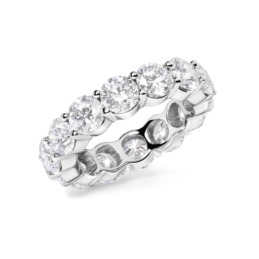 White metal ring with round white gemstones in shared prong setting, shown in a close-up angled view.