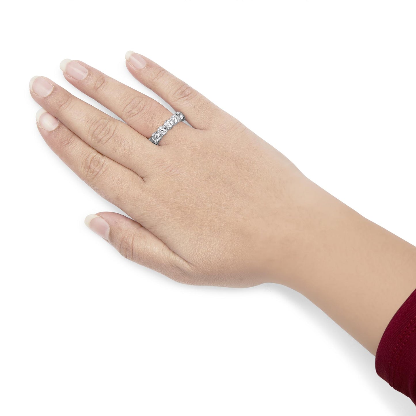 Hand wearing a white metal ring with round white gemstones in shared prong setting, shown from top angle.