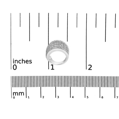 Top-down view of a white metal ring with multiple rows of shared prong-set white princess-shaped gemstones, placed on a ruler for size reference.