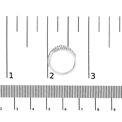 Top view of white metal ring with multiple rows of prong-set white princess-shaped gemstones, placed on a ruler for size reference.