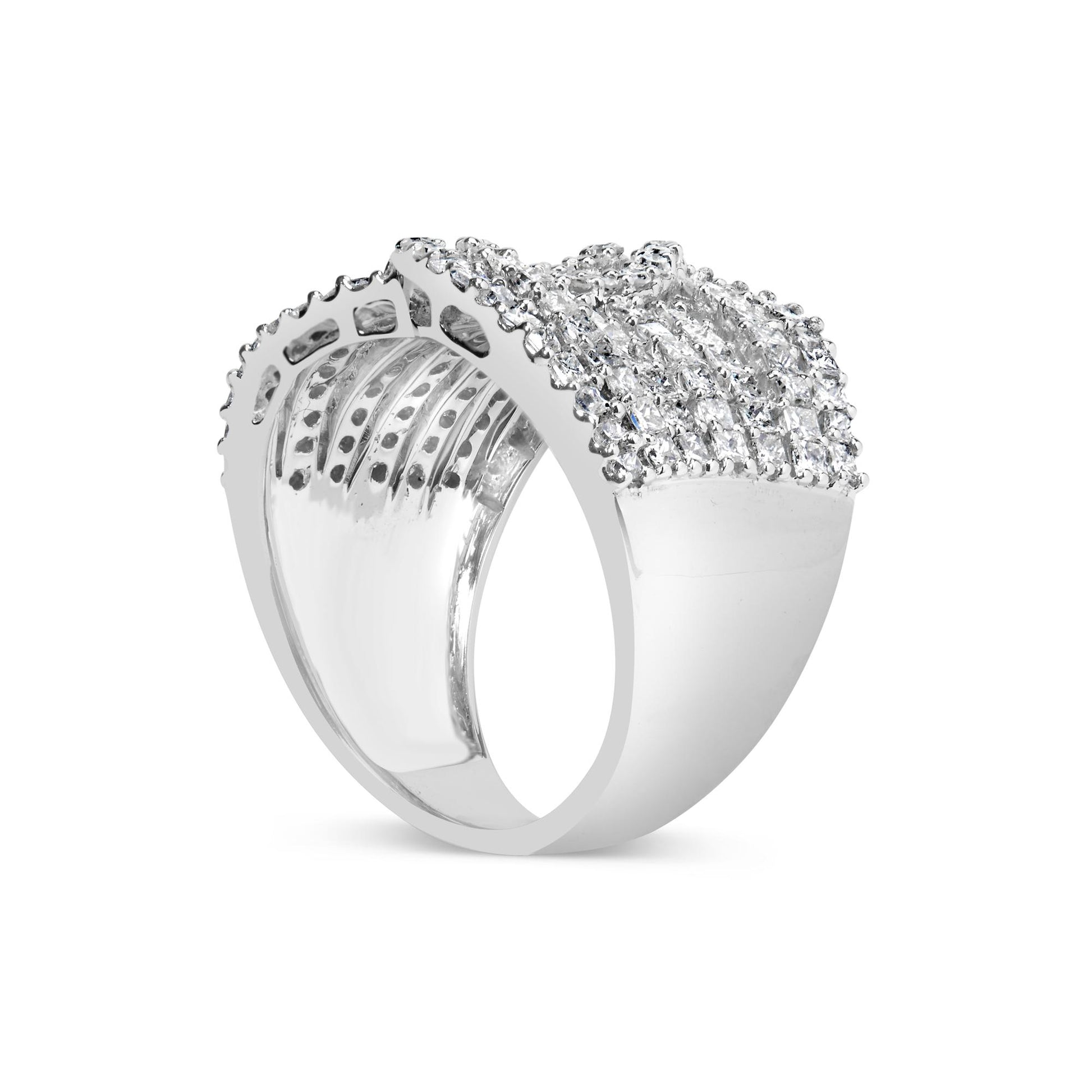 White metal ring viewed from an angled side showing a wide band encrusted with rows of small princess-shaped gemstones in an invisible setting and round gemstones in prong settings on top.