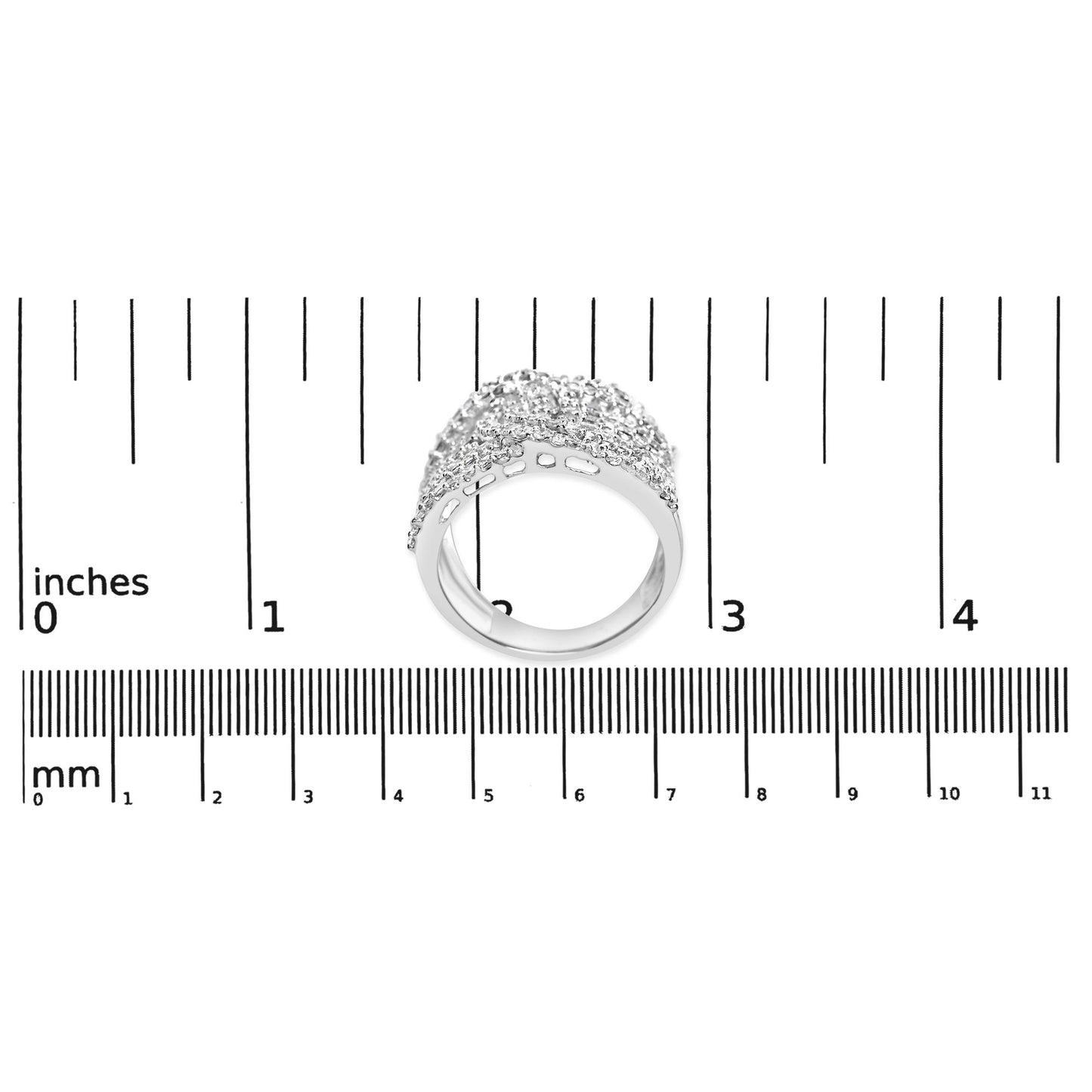 White metal ring with princess shape gemstones in an invisible setting and round shape gemstones in prong settings, shown from a slightly tilted side angle on a ruler for size reference.