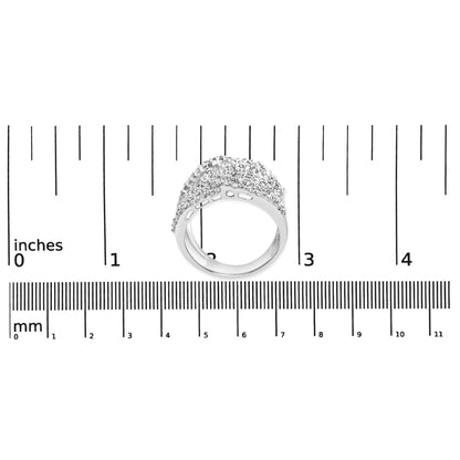 White metal ring with princess shape gemstones in an invisible setting and round shape gemstones in prong settings, shown from a slightly tilted side angle on a ruler for size reference.