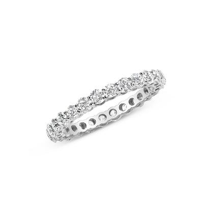 Close-up angled view of a white metal ring with a continuous row of round white gemstones in prong settings around the band.