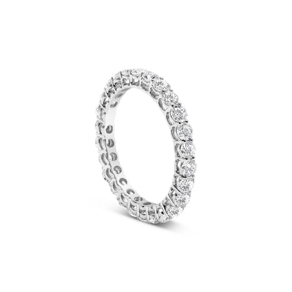 White metal ring with round white gemstones in prong settings encircling the band, shown at a slight angle.