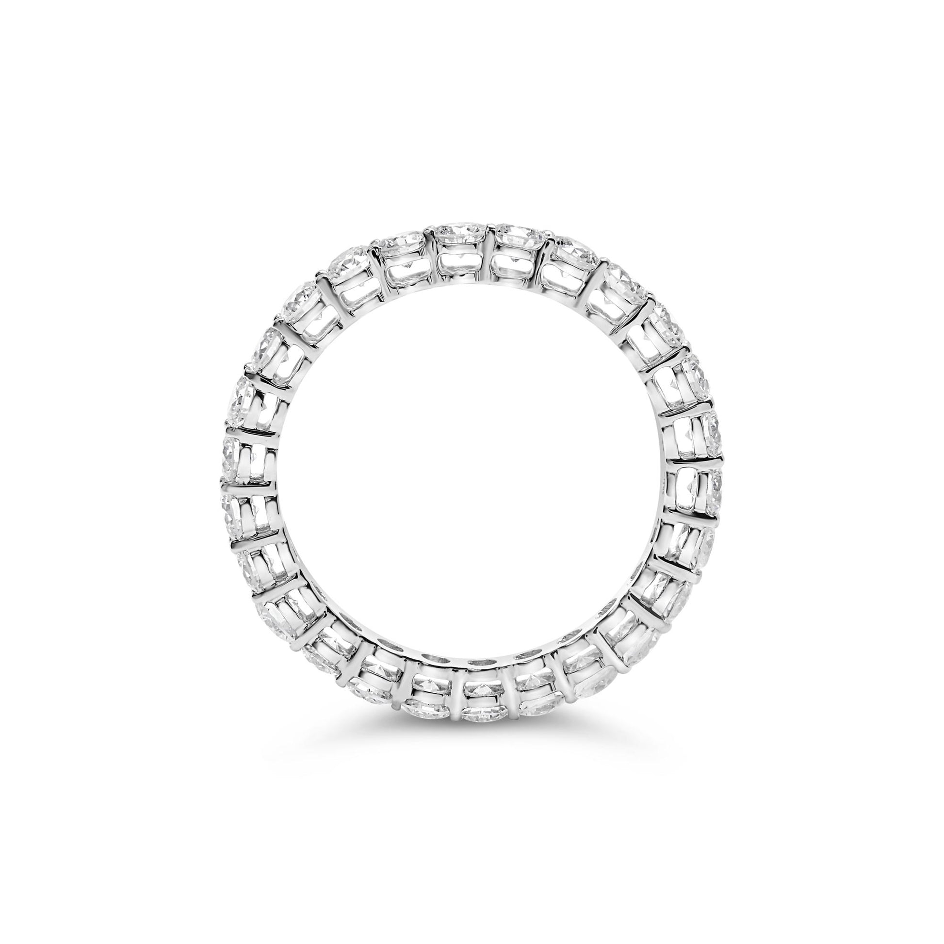 Top-down view of a white metal ring featuring a continuous row of round white gemstones in prong settings encircling the band.