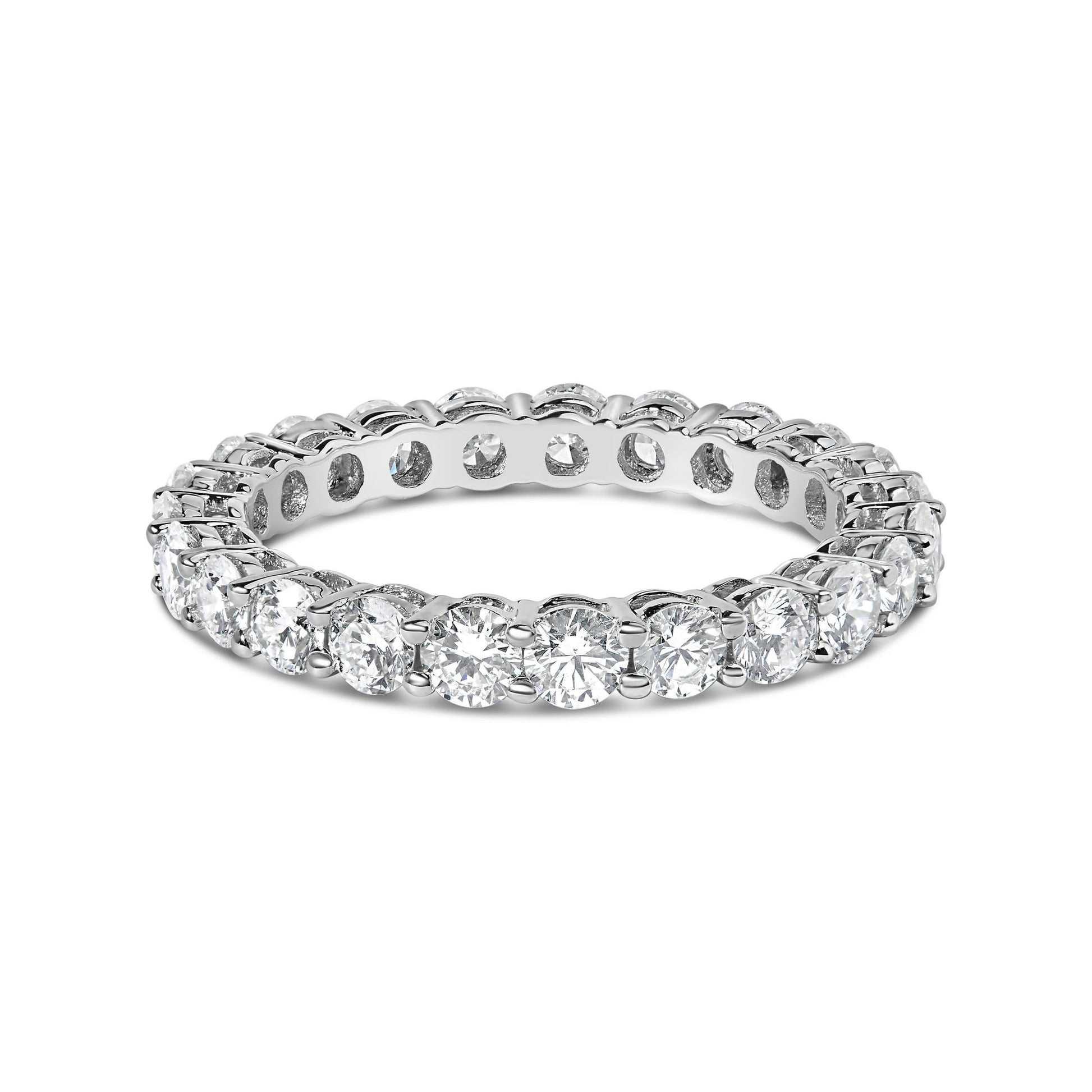 White metal eternity ring with round white gemstones in a shared prong setting, shown in a close-up angled view.