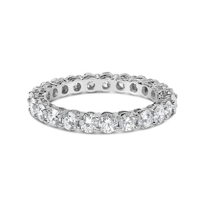 White metal eternity ring with round white gemstones in a shared prong setting, shown in a close-up angled view.