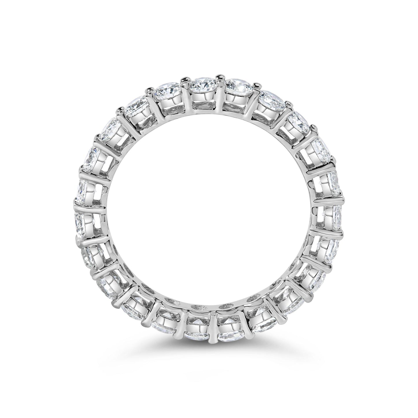 Top-down close-up of a white metal eternity band ring featuring round white gemstones in a shared prong setting encircling the entire band.