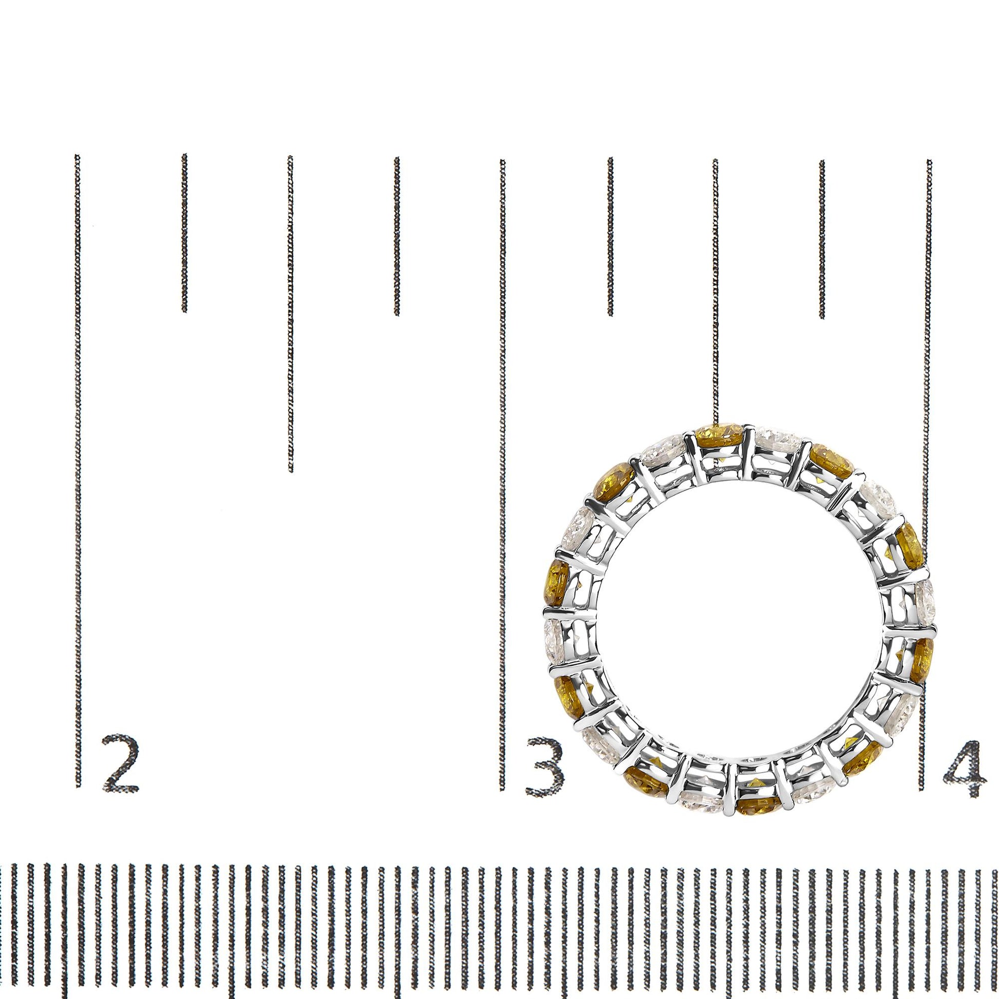 Top-down view of a white ring featuring alternating prong-set yellow and white round gemstones, placed on a ruler for size reference.