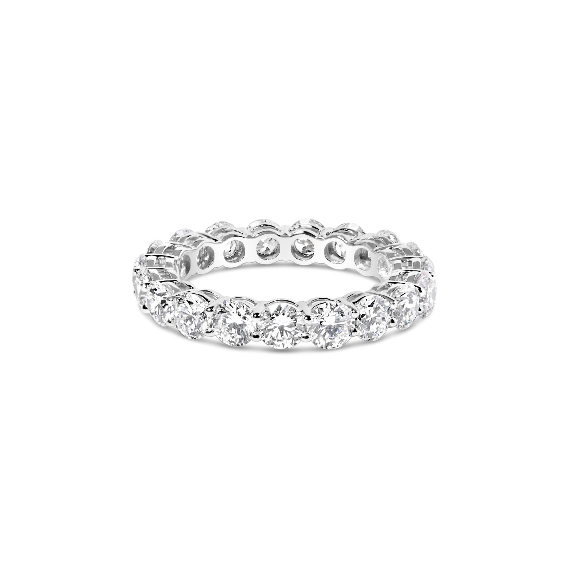 White metal eternity ring with round white gemstones in prong settings viewed from a front angle on a white background.